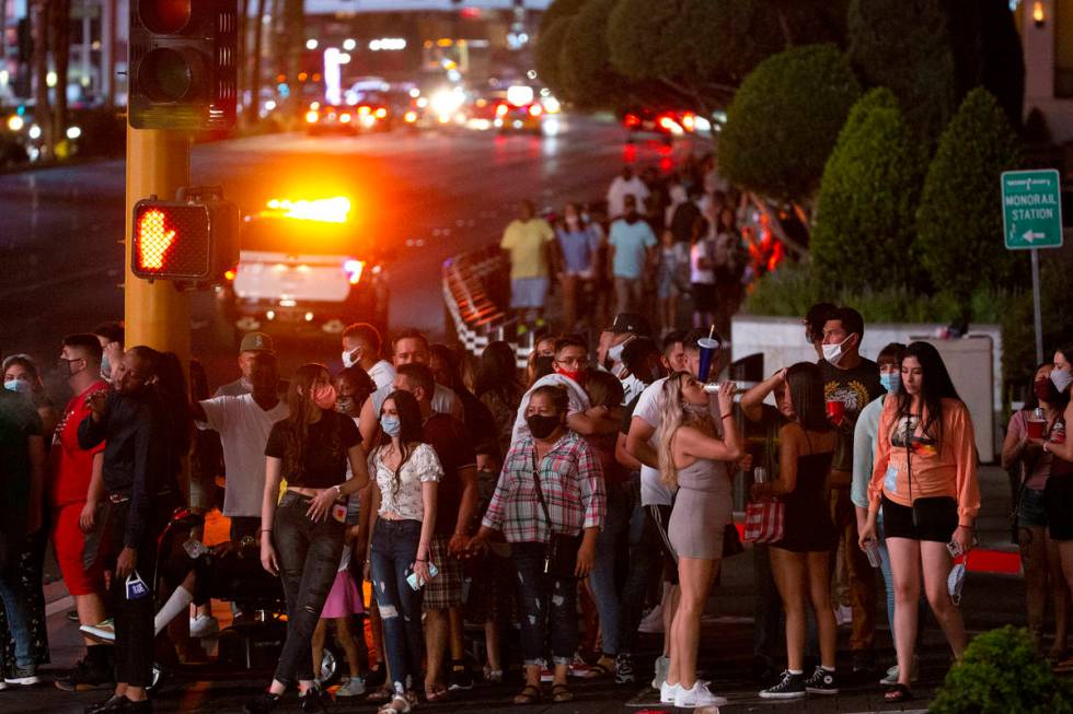 Visitors wait to cross the street outside Caesars Palace on the Strip during Labor Day weekend ...