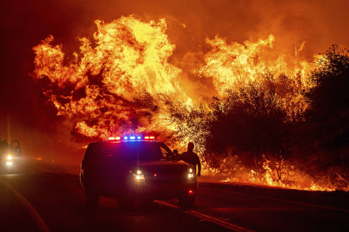 Flames lick above vehicles on Highway 162 as the Bear Fire burns in Oroville, Calif., on Wednes ...
