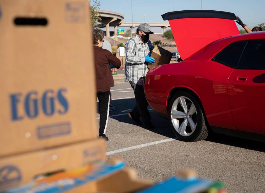 Volunteers Christina Bailey, left, Huberto Sandoval, center, place food in the trunk of a pers ...