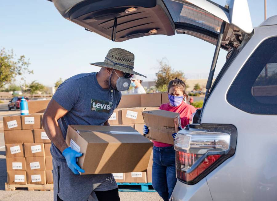 Volunteer Leonid Tuiasosopo, left, and Nicole McKinney, right, place food in the back of a pers ...