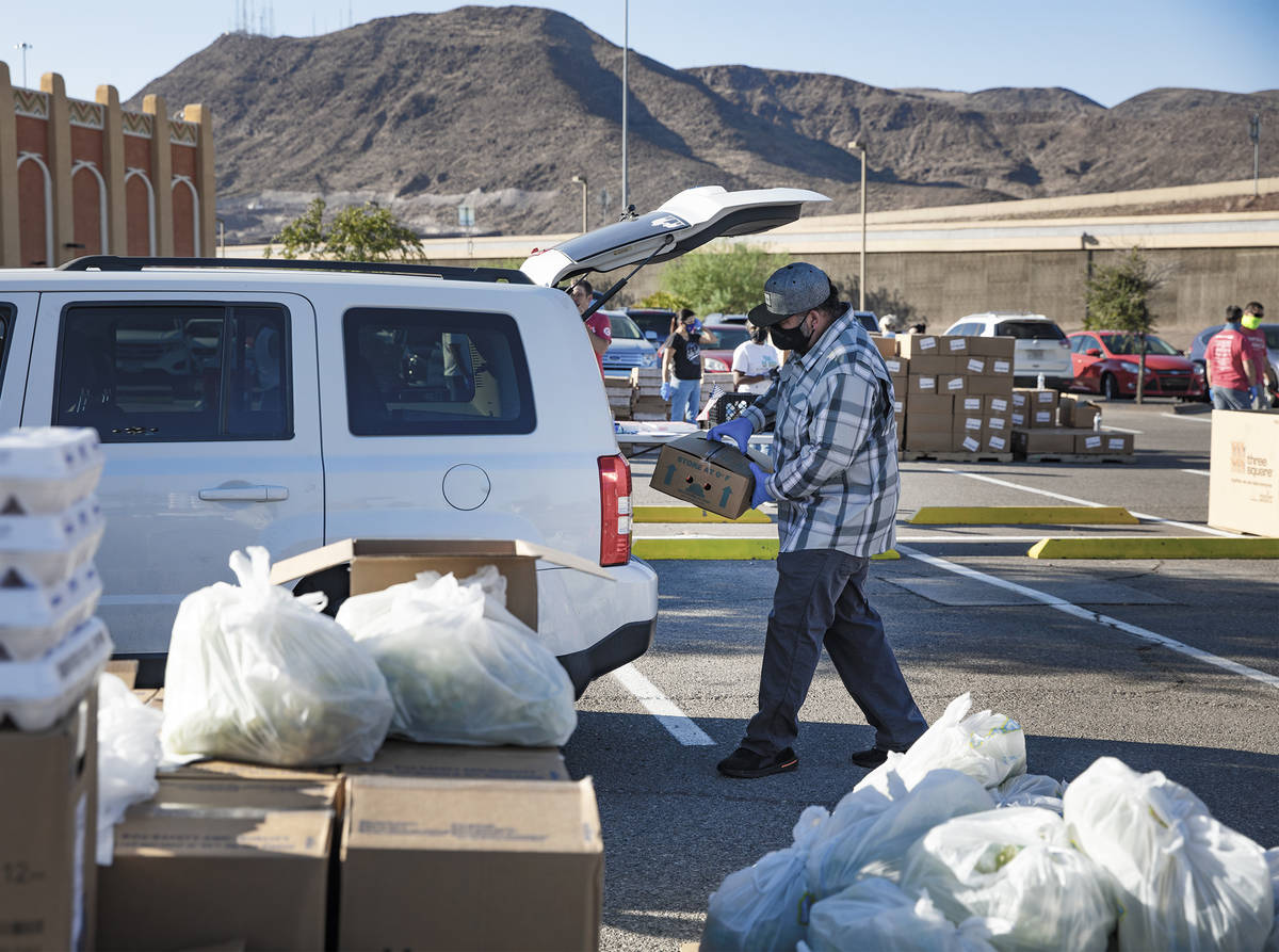 Volunteer Huberto Sandoval places food in the back of a person's car at the new drive-thru dist ...