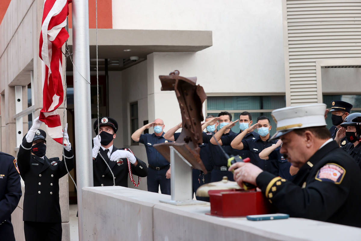 Las Vegas firefighter Lisa Leonard, left, and engineer Brian Dietz raise a flag that flew at th ...