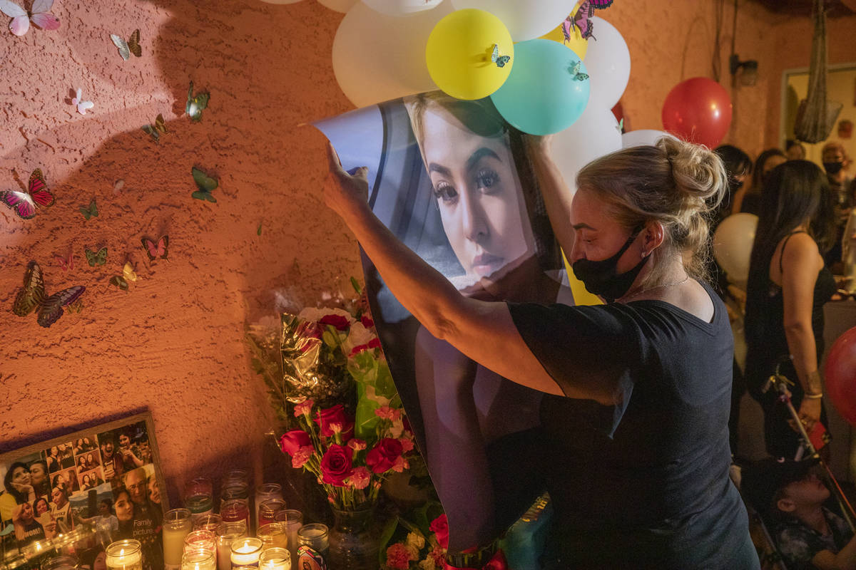 Mother of victim Lesly Palacio, Aracely Palacio, hangs up a photo of her daughter during a vigi ...