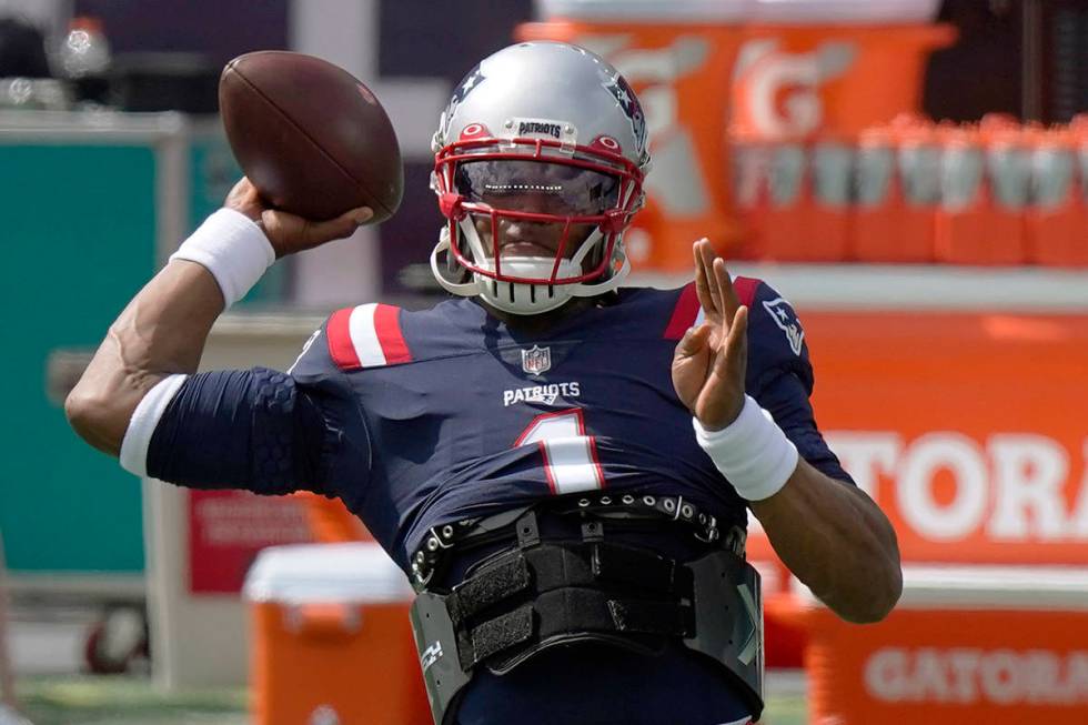 New England Patriots quarterback Cam Newton warms up before an NFL football game against the Mi ...