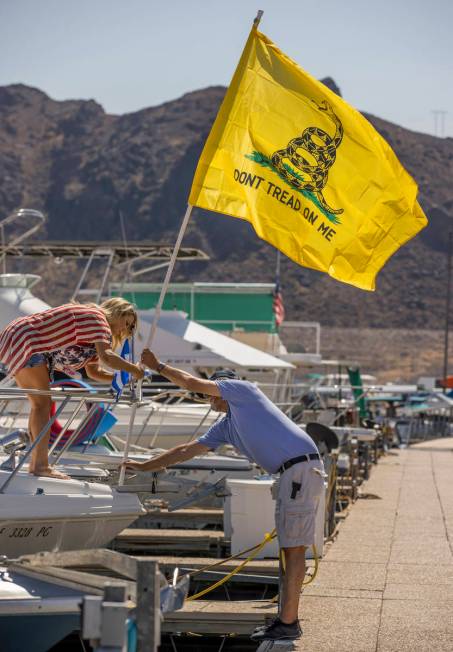 Event organizer Christine Snedden, left, helps to secure a flag with Jerry Dusa as they prepare ...