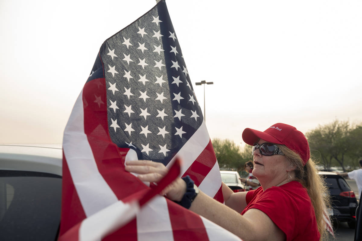 Make Nevada Red supporter Cindy Pegram, 61, of Henderson, attaches a flag to her car at the sta ...