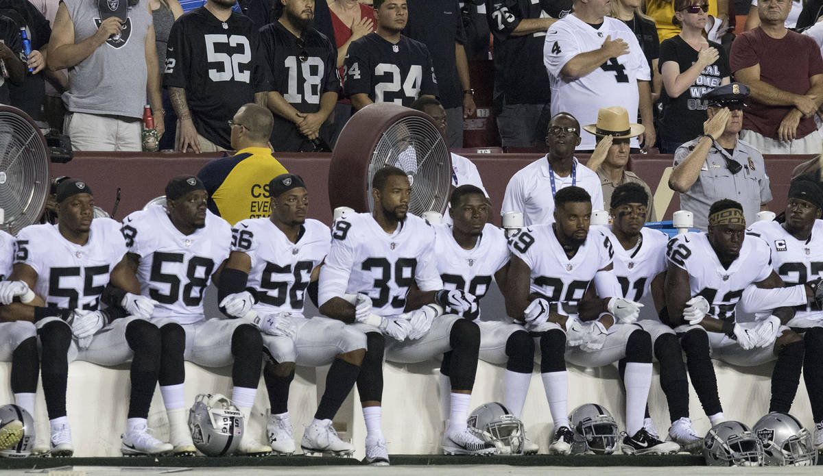 Some of the Oakland Raiders interlock arms and sit during the national anthem before their game ...