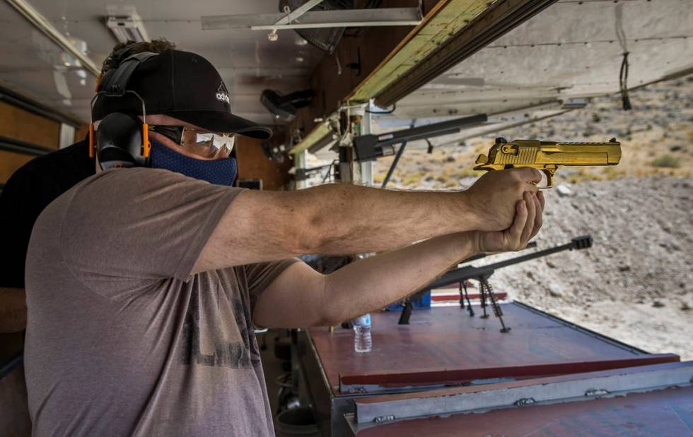 Christopher Lawrence aims a titanium gold Desert Eagle pistol on the Adrenaline Mountain gun ra ...