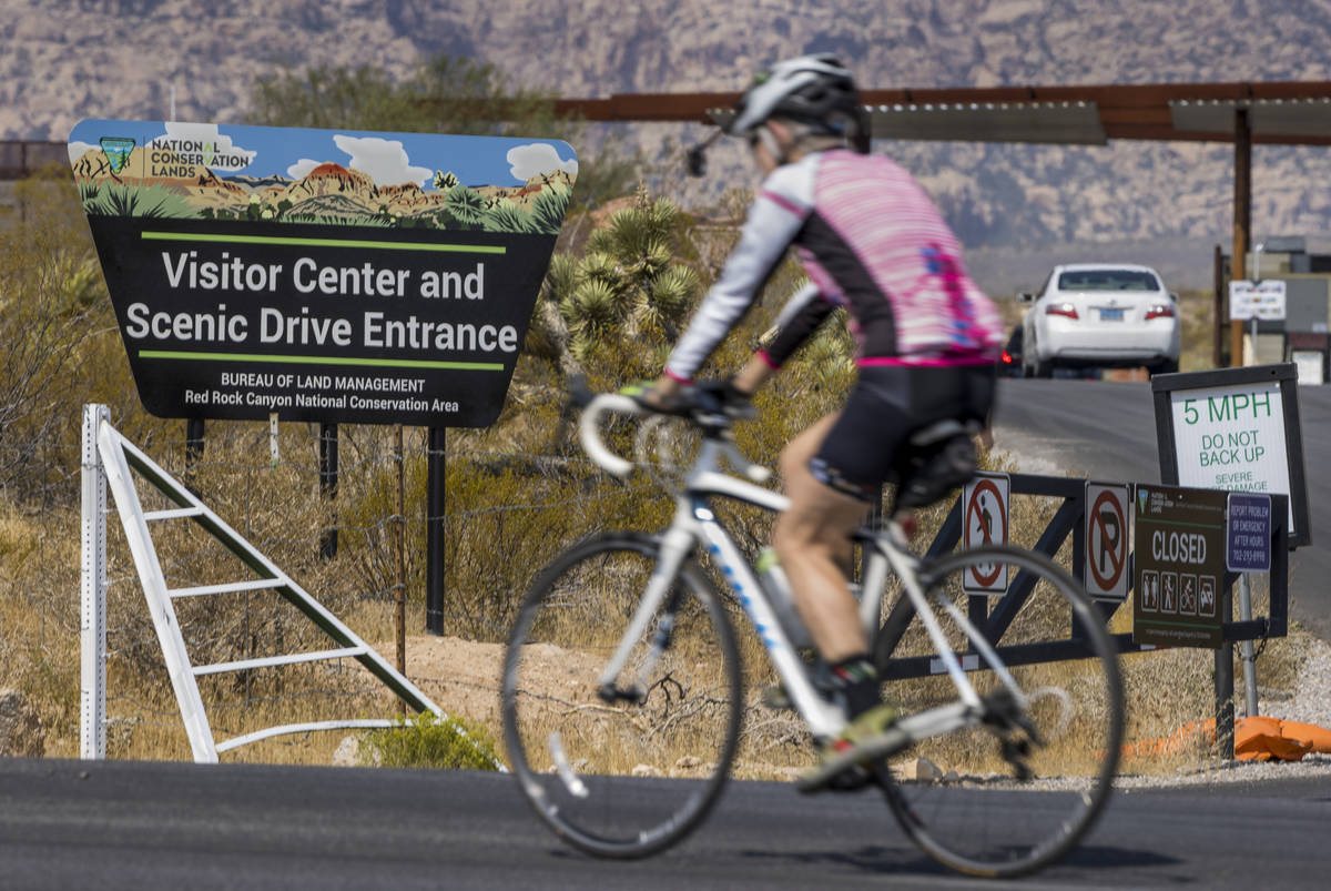 A cyclist passes an entrance marker for the Red Rock Canyon National Recreation Area near Las V ...