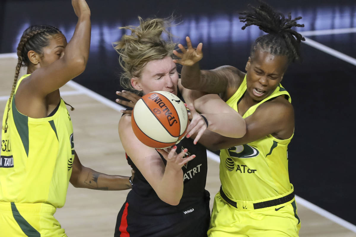 Las Vegas Aces' Carolyn Swords, center, collides with Seattle Storm's Epiphanny Prince, right, ...