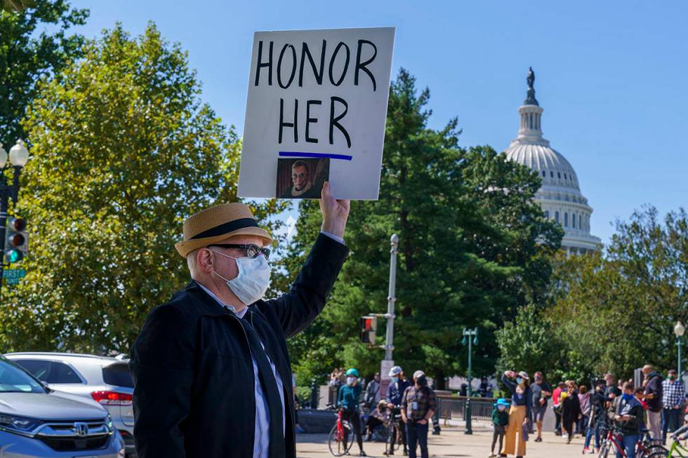 A man holds up a sign in honor of the late Justice Ruth Bader Ginsburg, as people gather at the ...
