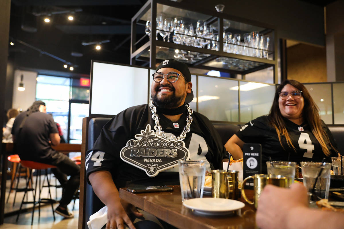 Mike Aguiniga, left, watches the Raiders first home game next to his wife Madi Aguiniga, right, ...