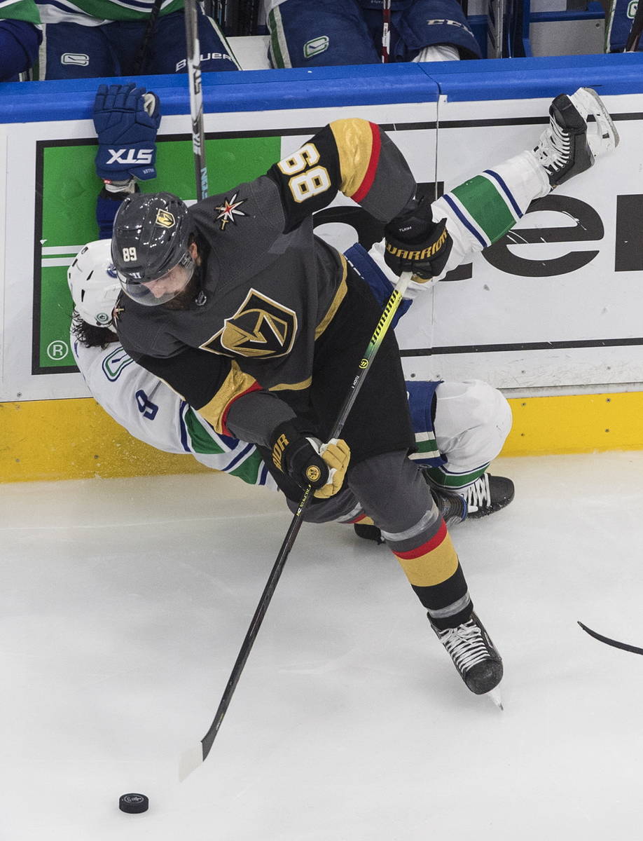 Vancouver Canucks' J.T. Miller (9) is checked by Vegas Golden Knights' Alex Tuch (89) during se ...
