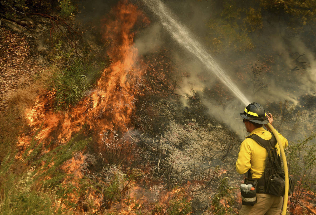 A firefighter puts out a hot spot along Highway 38 northwest of Forrest Falls, Calif., as the E ...