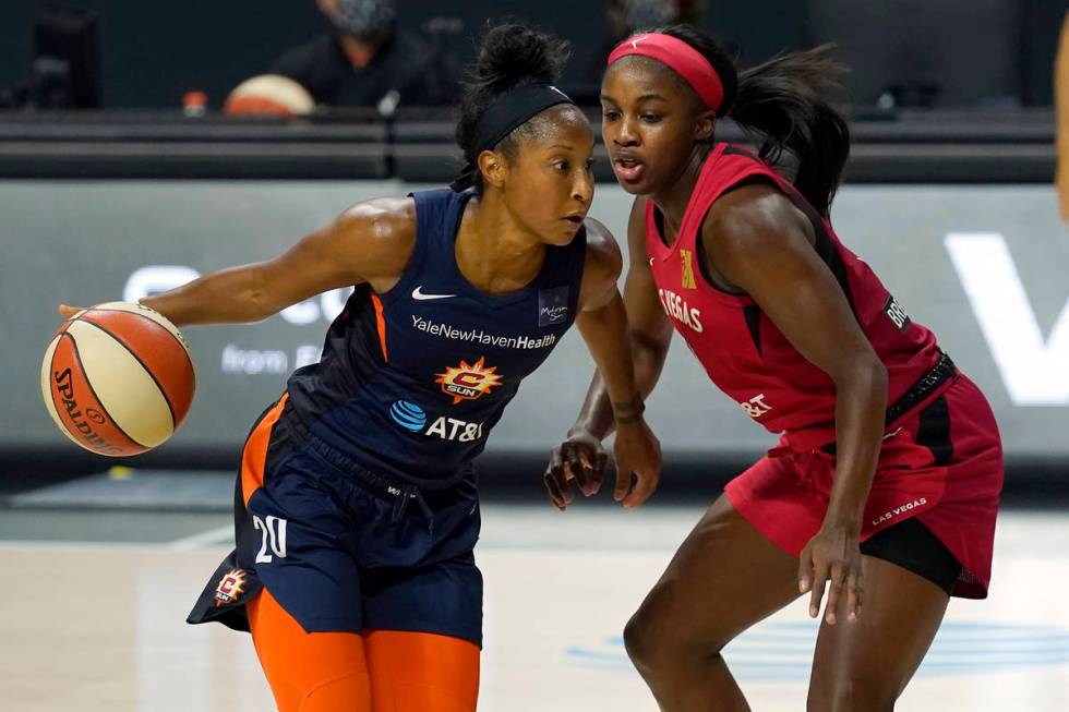 Connecticut Sun guard Briann January (20) drives around Las Vegas Aces guard Jackie Young (0) d ...