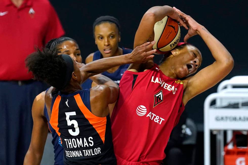 Las Vegas Aces center A'ja Wilson and Connecticut Sun guard Jasmine Thomas (5) battle for a reb ...