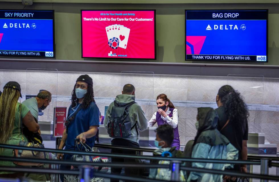 Delta Airlines passengers wait in the check in area as COVID-19 safety precautions are in place ...