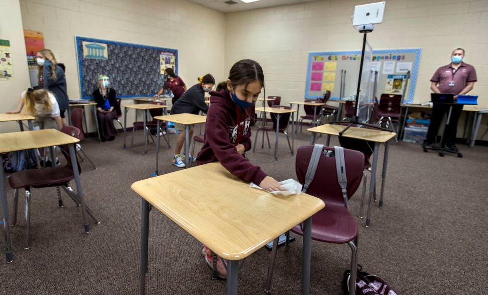 Student Alyssa Kazemi, 11, wipes down her desk with others in teacher Brandon Buskirk's 6th gra ...