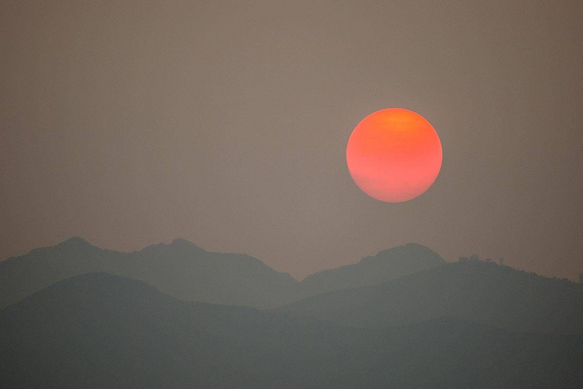 The sun, clouded by smoke from wildfires in California, sets behind Spring Mountains National R ...