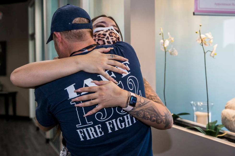 Seattle firefighter Dean McAuley, back, greets Natalia Baca whom he saved after a gunshot wound ...