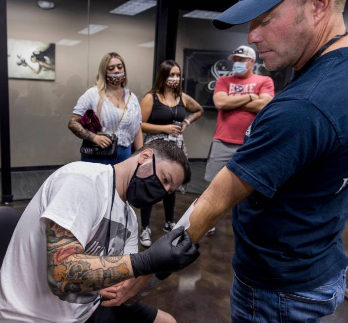 Tattoo artist Jim Sylvia, left, transfers a tattoo sketch onto Dean McAuley as Route 91 shootin ...