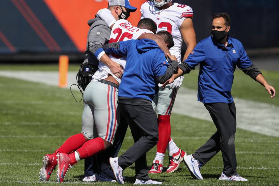 New York Giants running back Saquon Barkley is helped off the field after being injured against ...