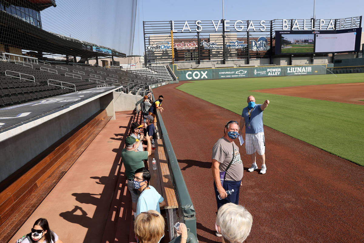 Gary Arlitz, director of game entertainment, gives a tour as fans check out the visitor dugout ...