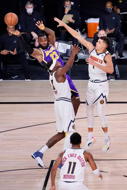 Los Angeles Lakers' LeBron James (23) passes the ball away from Denver Nuggets' Jerami Grant (9 ...