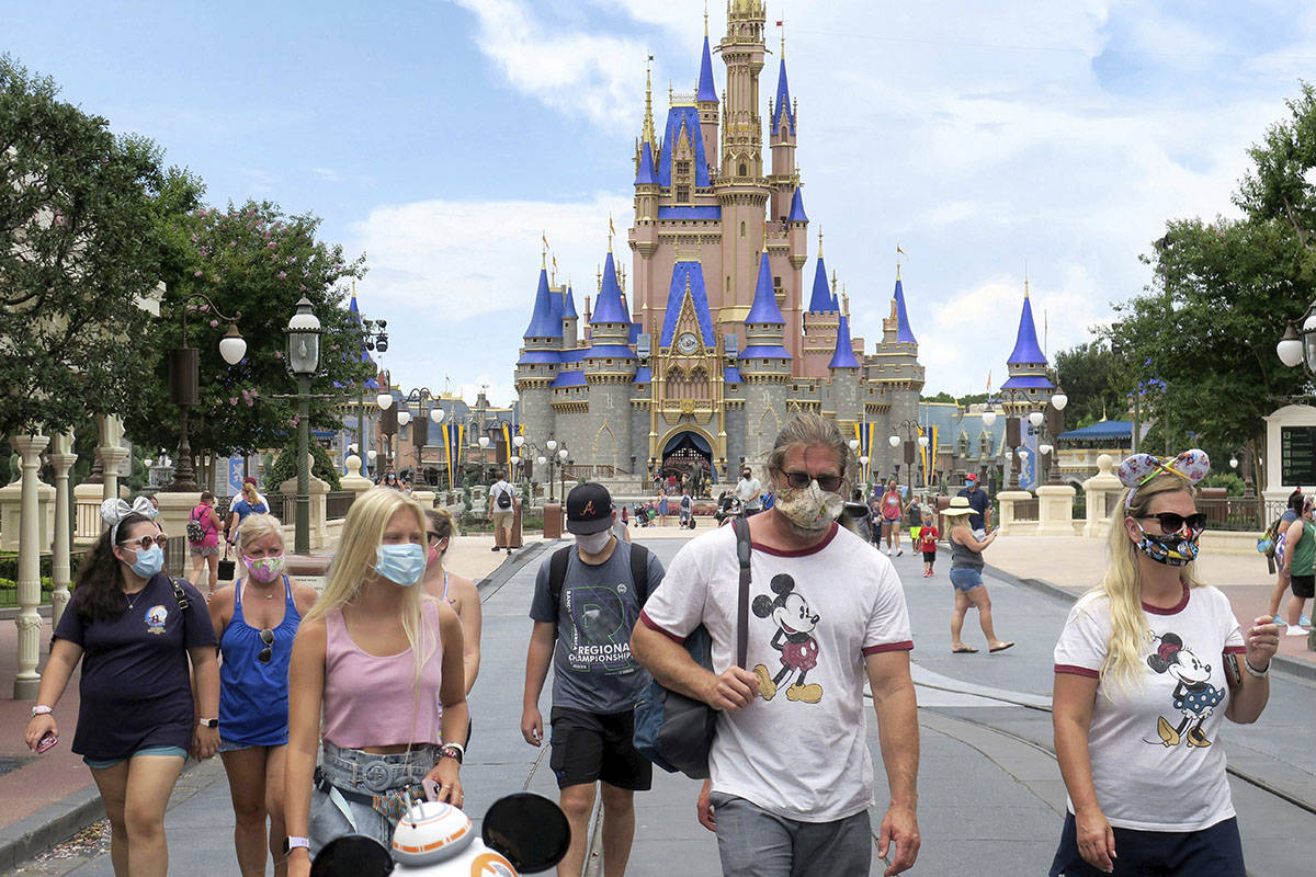 Guests wear masks as required to attend the official reopening day of the Magic Kingdom at Walt ...