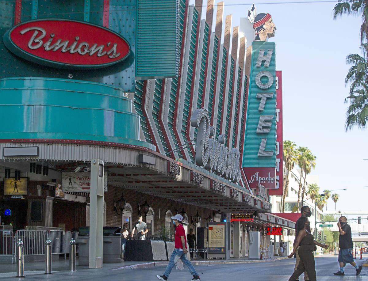 People walk across Fremont Street with Hotel Apache in the background in downtown Las Vegas on ...