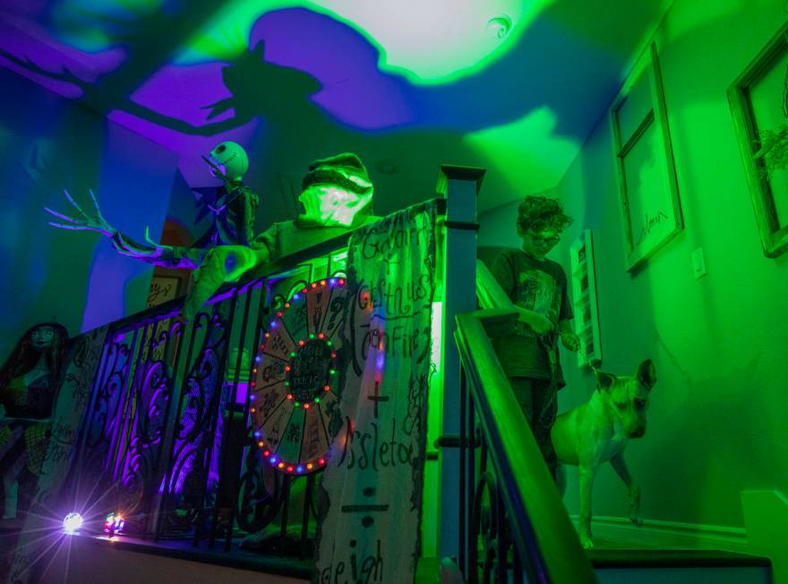 Evan Garcia, 10, walks his dog Jessie down the stairs of their Disney Halloween-themed home in ...