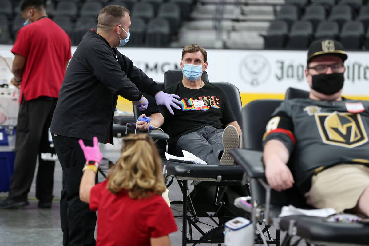 Dave Goucher, a Vegas Golden Nights television voice, center, participates during a blood donat ...