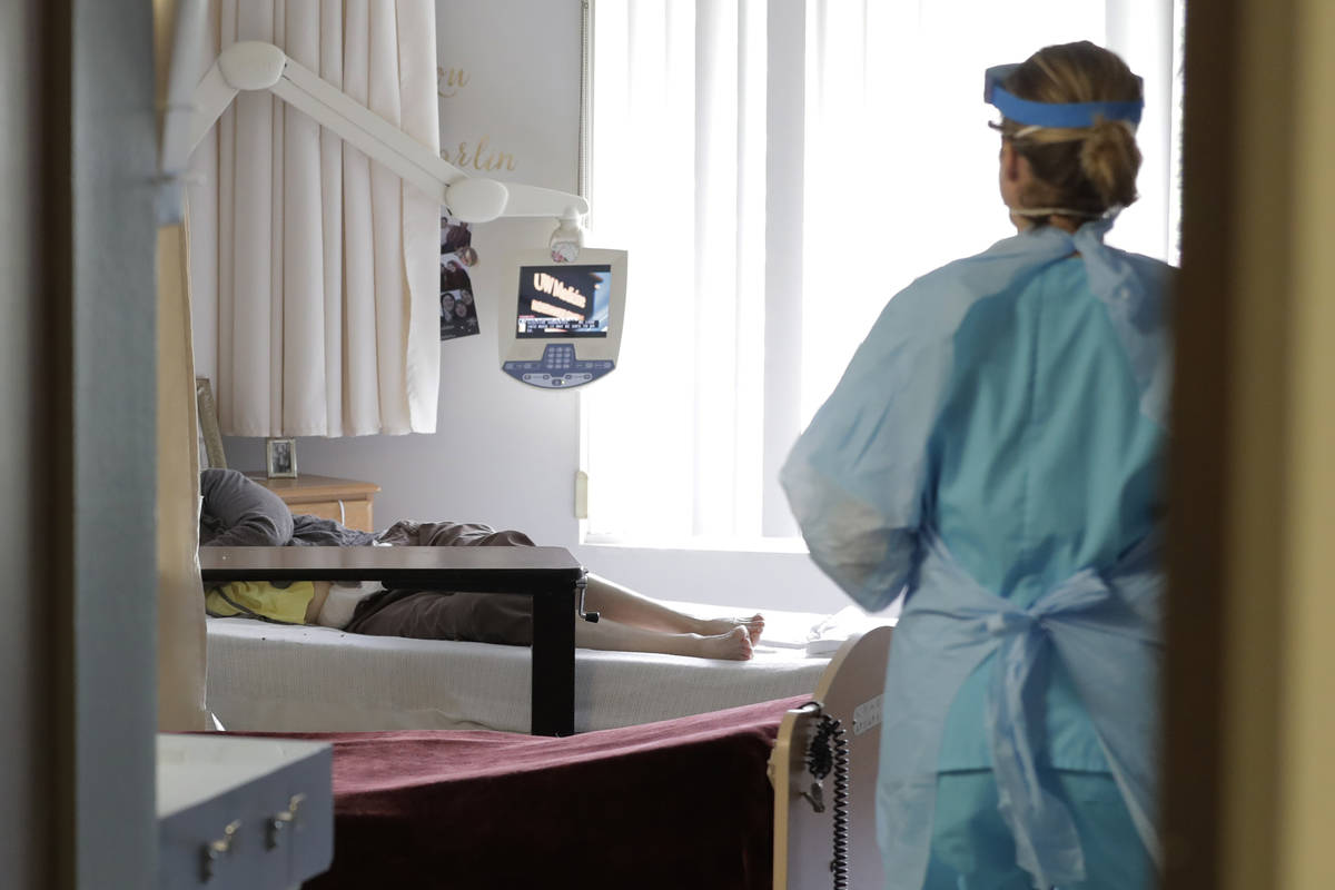 A health worker arrives to take a nose swab sample at a nursing and rehabilitation facility in ...