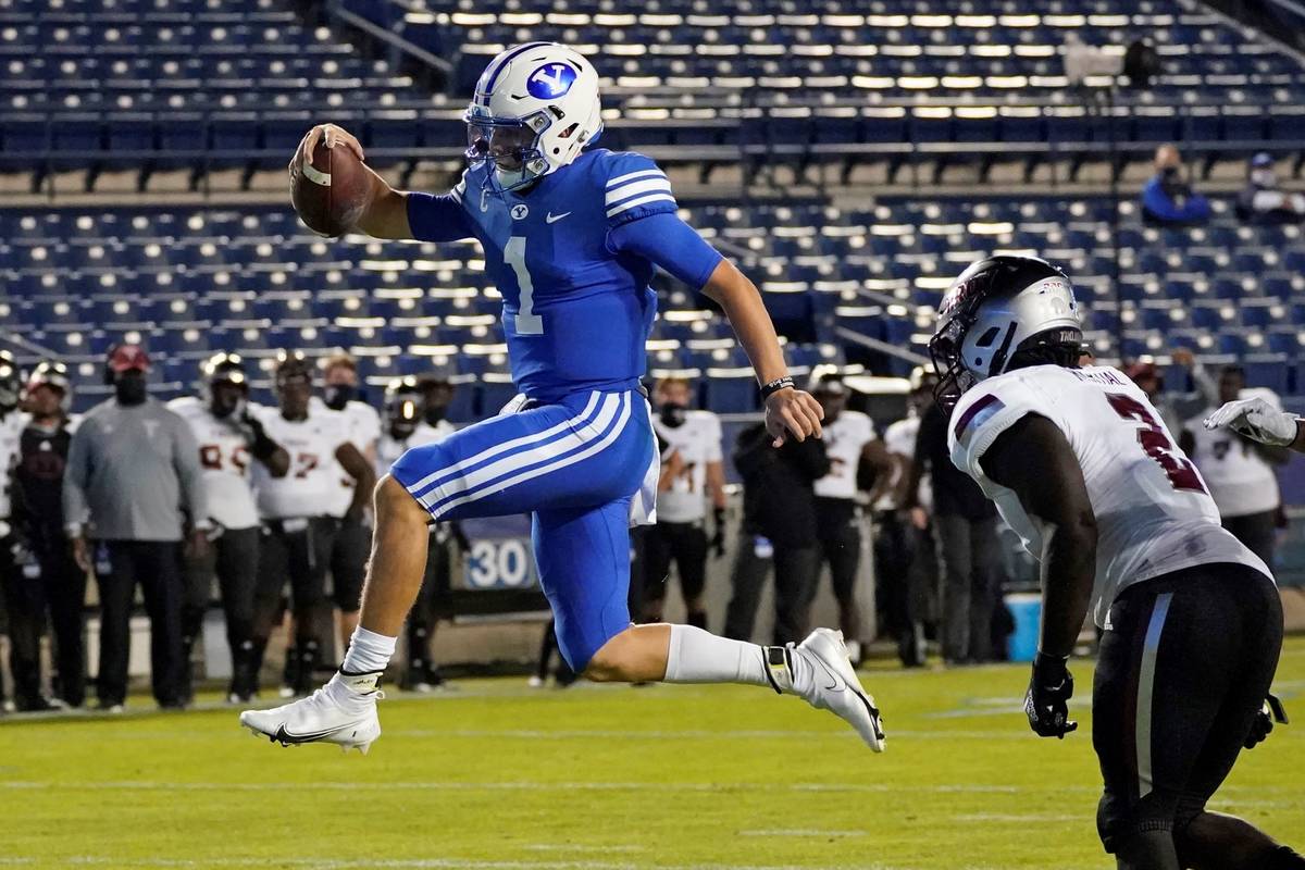 BYU quarterback Zach Wilson (1) leaps into the end zone, next to Troy linebacker Carlton Martia ...