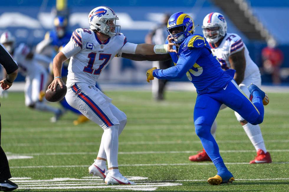 Buffalo Bills quarterback Josh Allen, left, tries to avoid pressure by Los Angeles Rams linebac ...