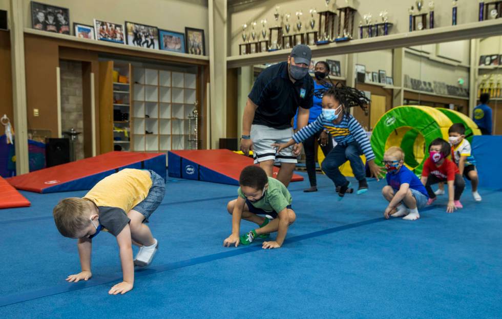 Instructor Mo Bonnet, center, encourages kindergarteners in frog jumps while exercising during ...