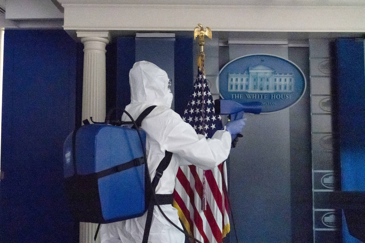 A member of the cleaning staff sprays The James Brady Briefing Room of the White House, Monday, ...