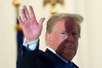 President Donald Trump waves from the Blue Room Balcony upon returning to the White House Monda ...