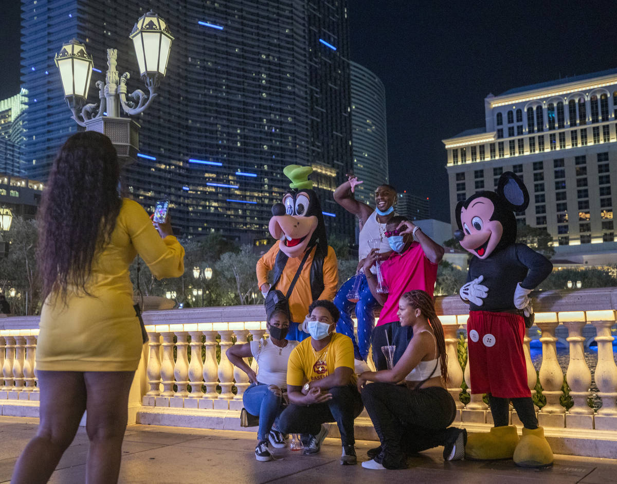 Tourists get their photo taken near the Bellagio hotel and casino fountains, late Friday night ...