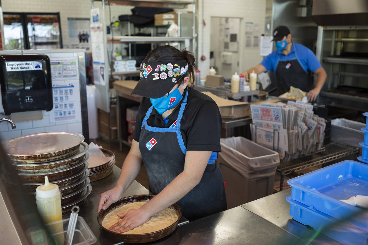 Domino's assistant manager Mayra Hernandez places dough in a pan at the Domino's located off of ...