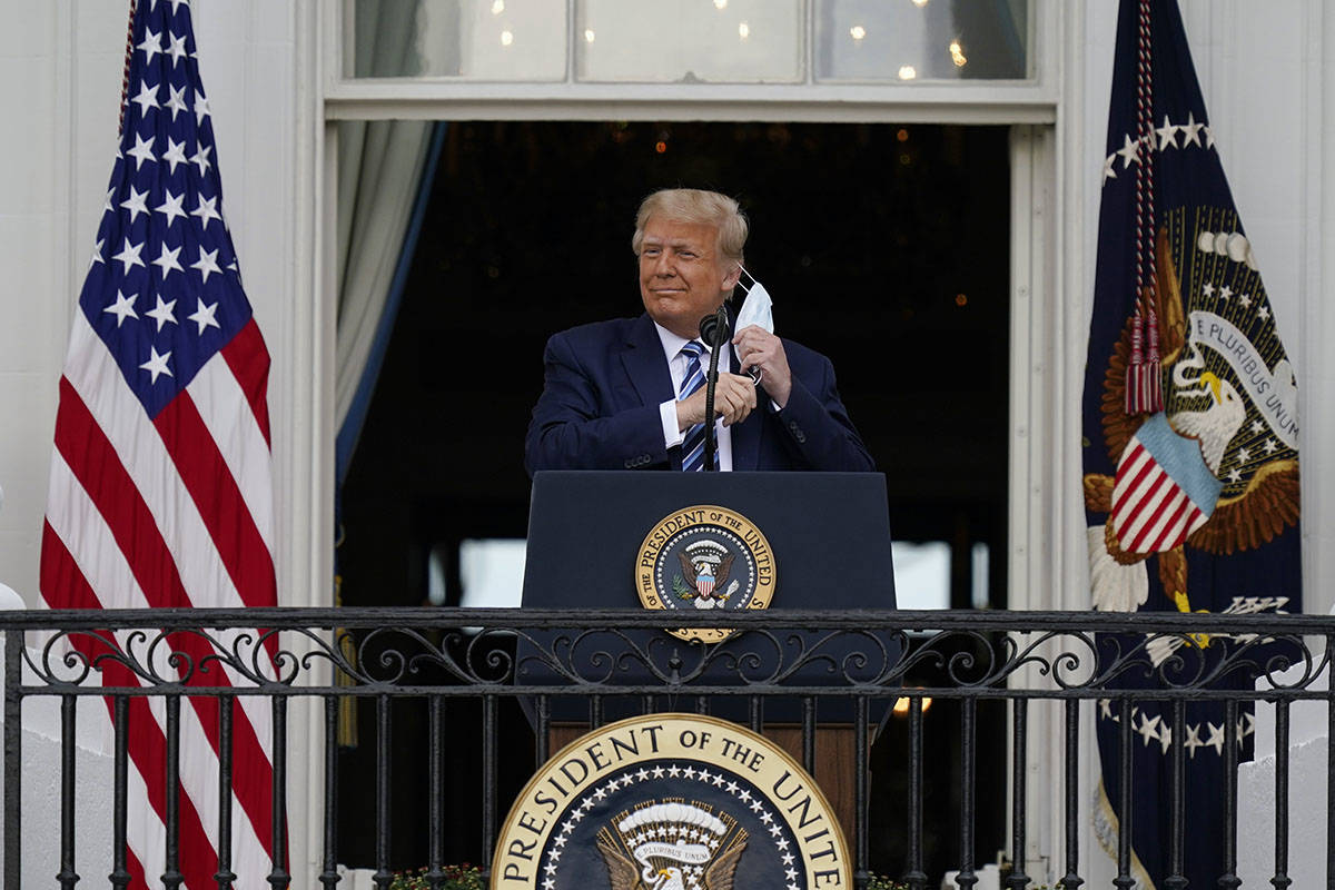 President Donald Trump removes his face mask to speak from the Blue Room Balcony of the White H ...