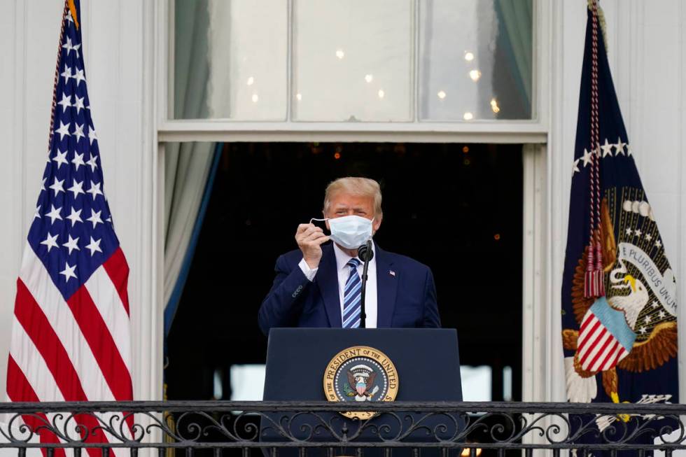 President Donald Trump removes his face mask to speak from the Blue Room Balcony of the White H ...