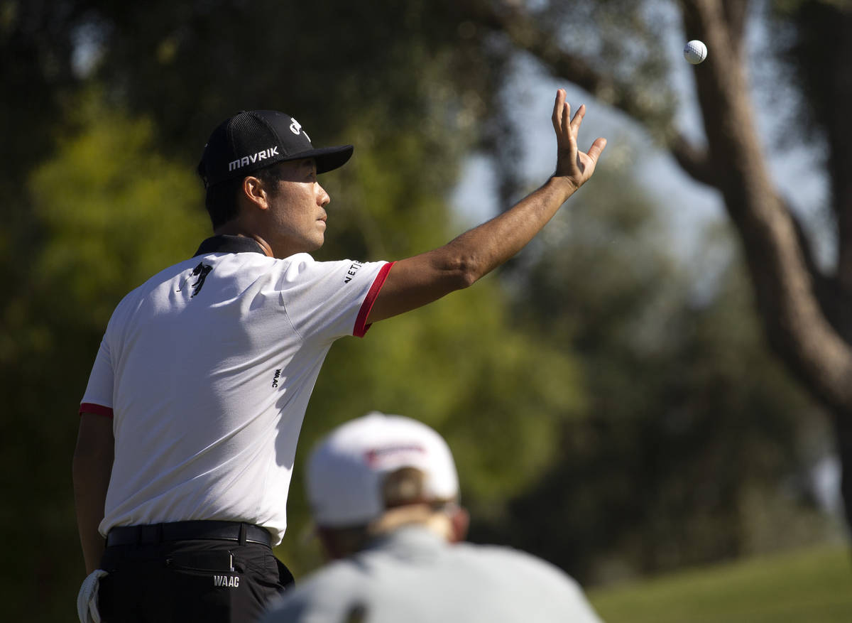 Kevin Na catches a ball from his caddy before putting the twelfth hole during the final round o ...