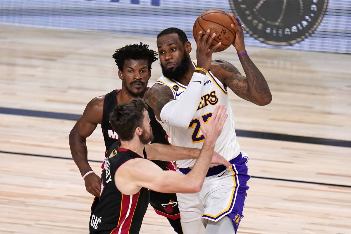 Los Angeles Lakers' LeBron James (23) drives against Miami Heat's Goran Dragic (7) and Jimmy Bu ...