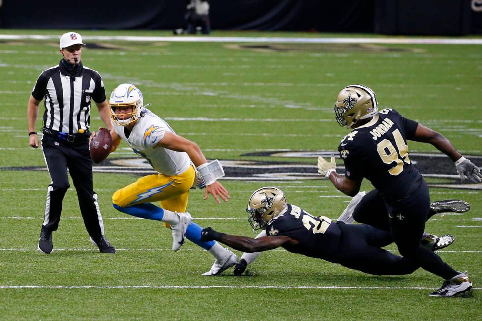 Los Angeles Chargers quarterback Justin Herbert scrambles under pressure from Los Angeles Charg ...