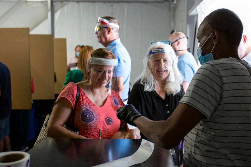 Toni James, right, hands Zahava Ram, left, her "I Voted" sticker after turning in her ...