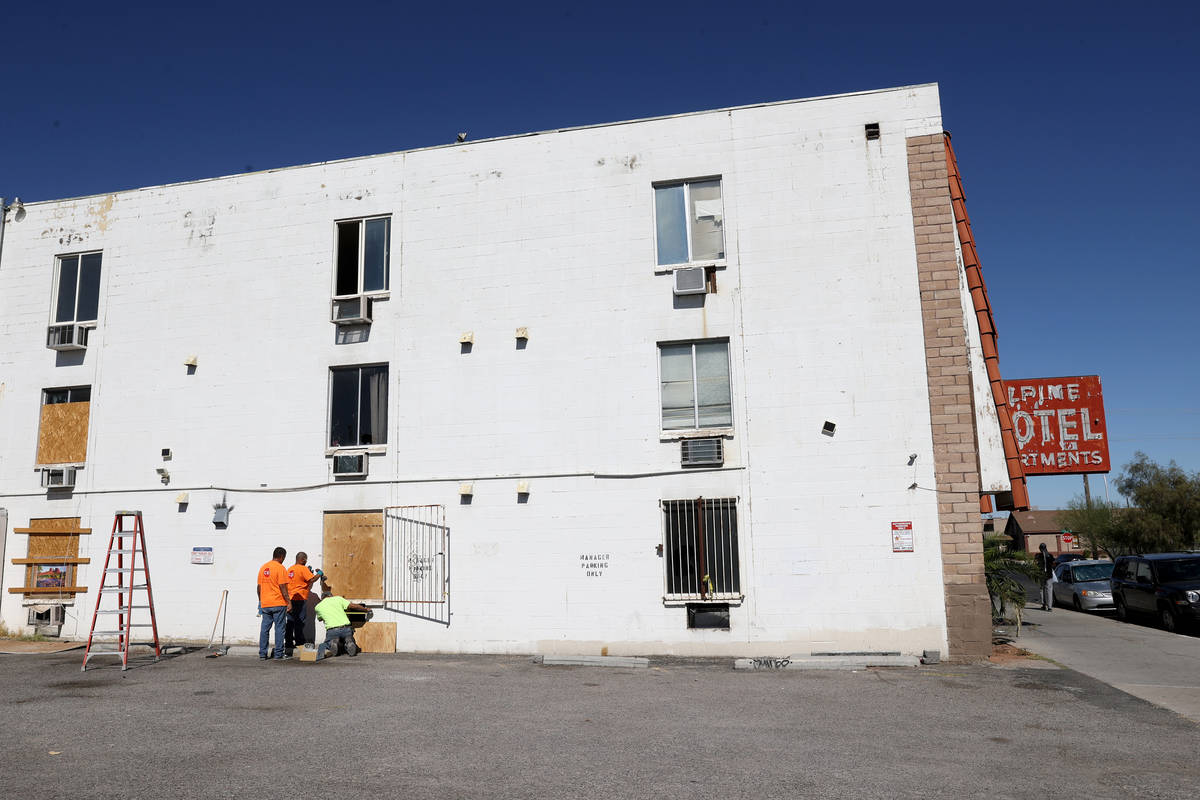 Workers board up windows at the Alpine Motel Apartments in downtown Las Vegas Thursday, Oct. 15 ...