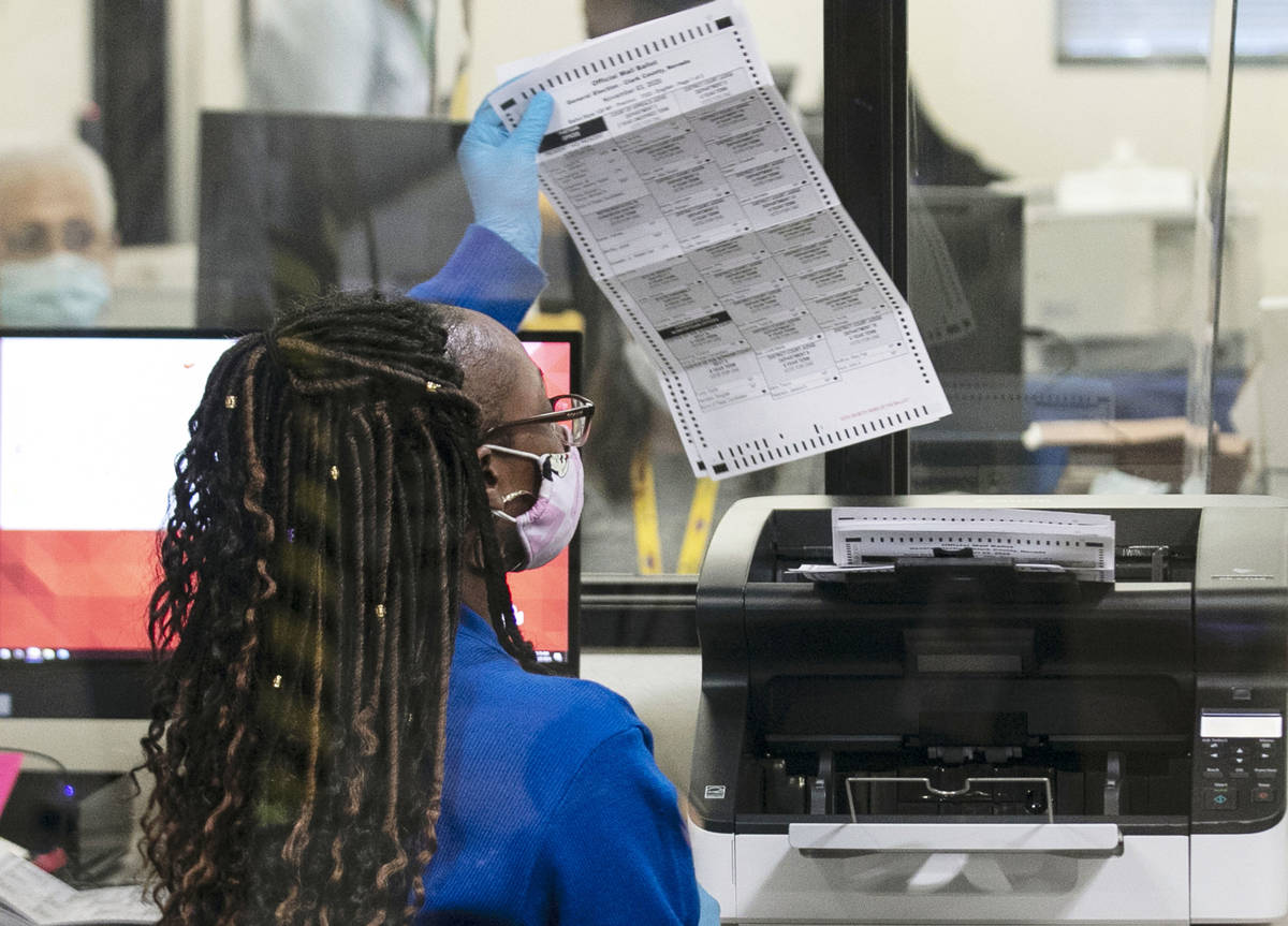 A Clark County election worker checks out a ballot as she prepares to scan it at the Election D ...