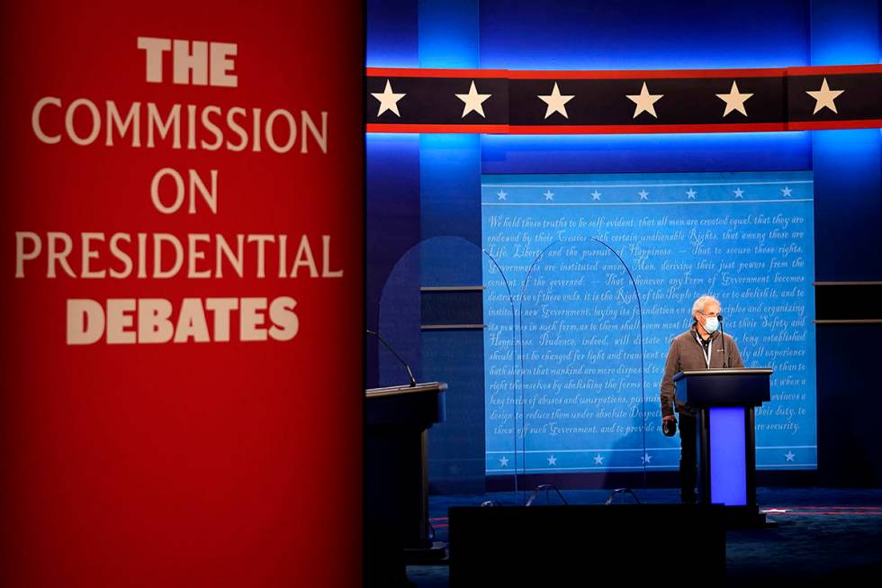 A member of the production crew stands at a podium near glass barriers to prevent the spread of ...