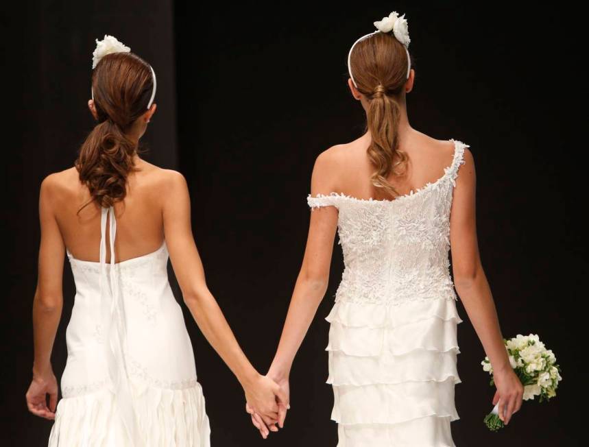 FILE -- In this Thursday, Oct. 23, 2014 file photo, models hold hands on the catwalk during a w ...